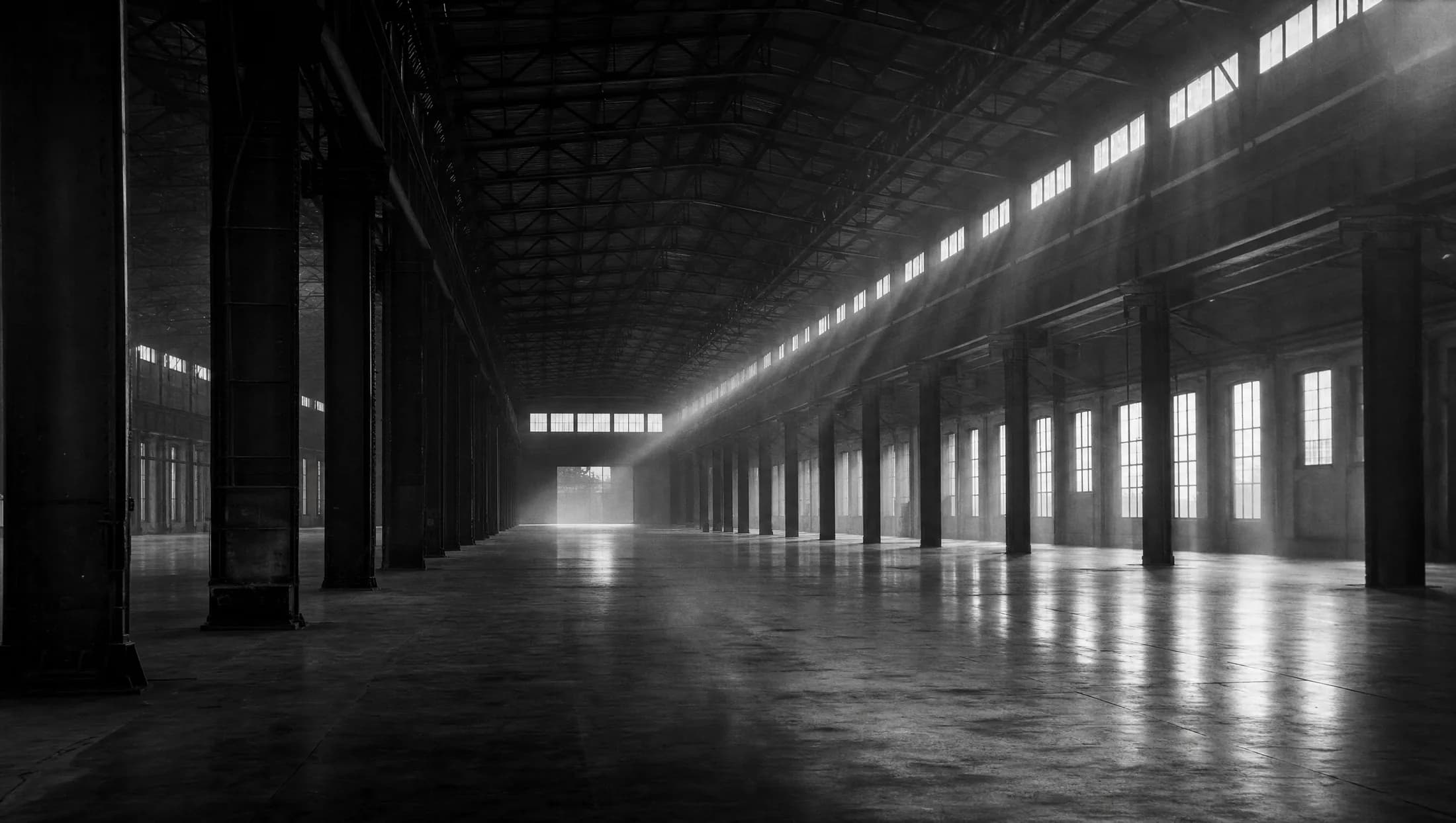 An immense empty industrial hall at dawn, between shifts